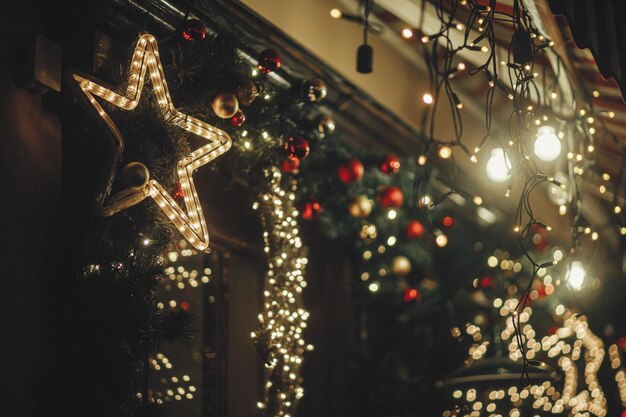 Feliz Natal Iluminação elegante de estrelas de Natal e luzes festivas em galhos de abeto à noite ao ar livre Decoração de natal moderna na rua da cidade Férias de inverno atmosférico na Europa