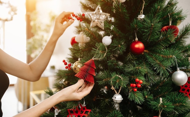 Feliz Natal Mãos Mãos abrindo presente de Natal com laço vermelho no fundo da árvore de Natal com luzes na sala festiva Fechar Feliz Natal