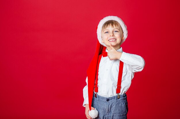 Feliz Natal Menino alegre bonito com chapéu de Papai Noel em fundo vermelho infância feliz