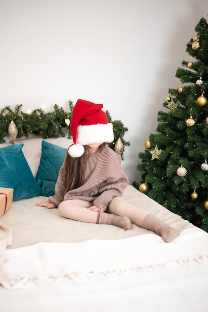 Feliz Natal Retrato de uma garota engraçada com um dente de leite caído no fundo de uma árvore de Natal com luzes acesas Espaço de estilo de vida para texto