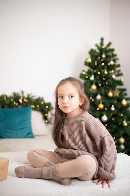 Feliz Natal Retrato de uma linda garota com um presente nas mãos contra o fundo de uma árvore de Natal decorada Estilo de vida