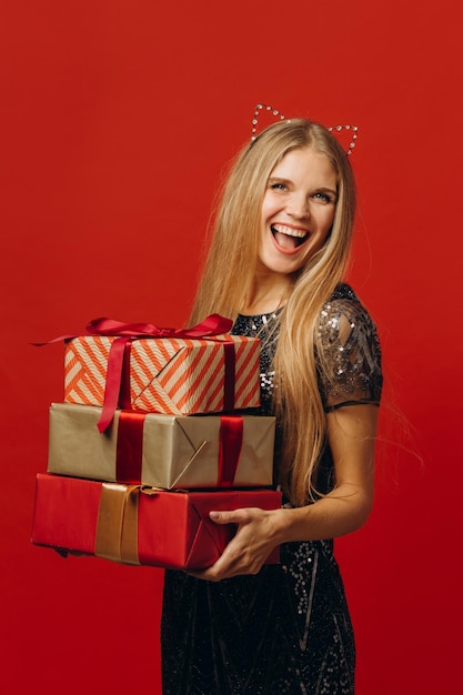 Feliz Natal, uma mulher loira feliz em um vestido festivo, segurando o retrato de presentes de Natal