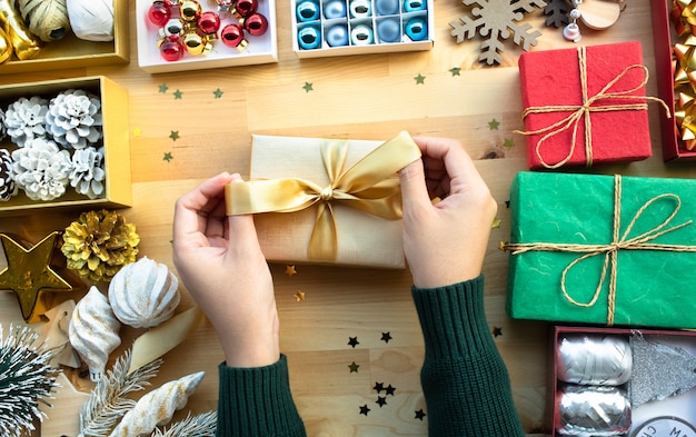 Feliz navidad con caja de regalo de decoración de mano femenina presente