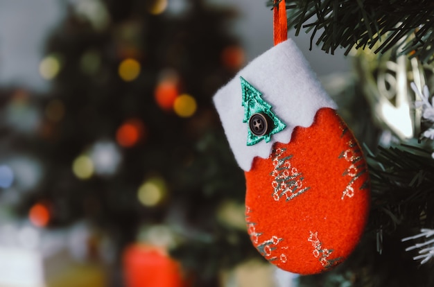 Feliz Navidad. Calcetín decorado en color rojo que cuelga en el árbol de navidad, familia de vacaciones, feliz año nuevo y feliz festival de navidad, efecto de tono de color vintage