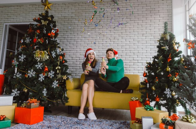 Feliz Navidad. Caucásica pareja dulce con sombrero rojo de santa divirtiéndose con papel de colores