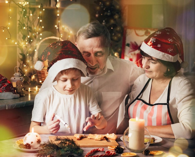 Feliz navidad concepto familia en la mesa de la cocina cocinar pan de jengibre felices abuelos y nieto