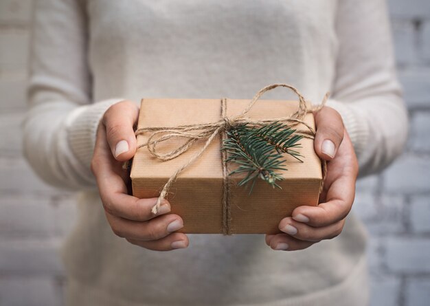 Feliz Navidad enhorabuena. Mujer sosteniendo una caja de regalo de papel artesanal, para Navidad y año nuevo regalo de vacaciones