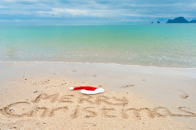 Foto feliz navidad escrita en arena de playa tropical