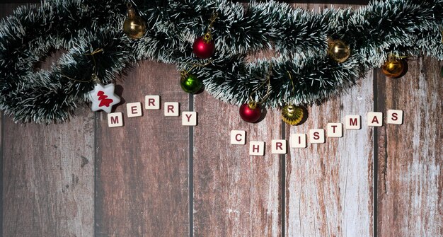 Feliz Navidad escrita con letras de un juego y adornos navideños sobre un fondo de madera