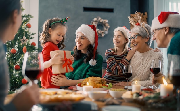 Feliz Navidad. La familia feliz está cenando en casa. Celebración festiva y unión cerca del árbol.