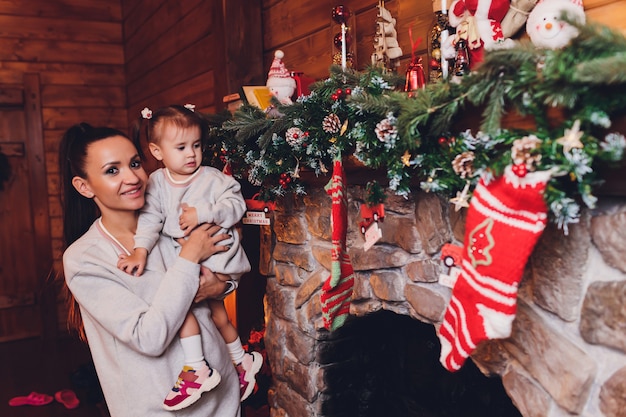 Feliz Navidad y Felices Fiestas Alegre mamá y su hija linda niña intercambiando regalos. Padre y niño divirtiéndose cerca de árbol de Navidad en el interior. Familia amorosa con regalos en la habitación.