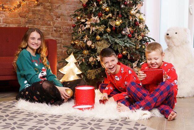 Feliz navidad y felices fiestas alegres lindos hermanos bebés abriendo regalos niños en pijama hav ...