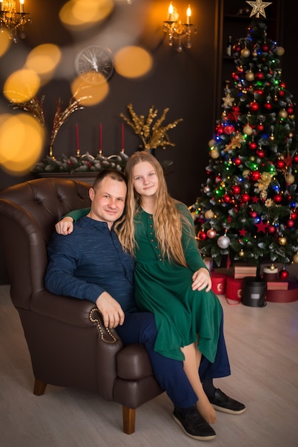Feliz Navidad y Felices Fiestas. familia, padre e hija en el fondo de un árbol de Navidad.
