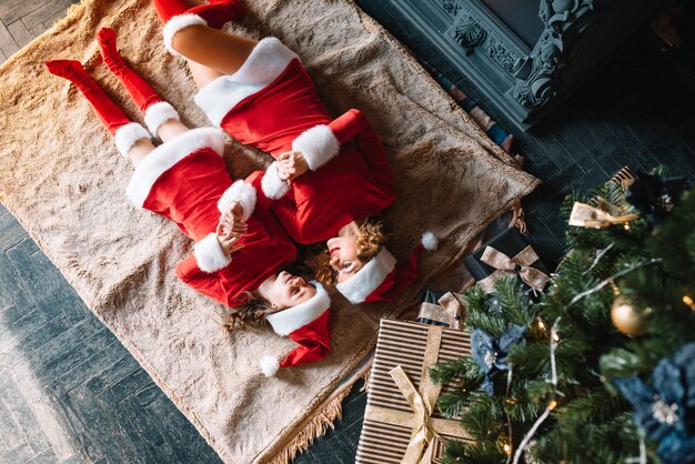 ¡Feliz Navidad y Felices Fiestas! Hermosa madre con hija pequeña en trajes de Navidad pasan tiempo juntos cerca del árbol de Navidad.