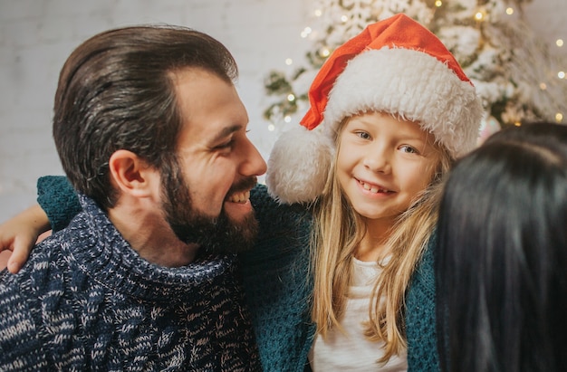 Feliz Navidad y felices fiestas Madre alegre, padre y su linda hija intercambiando regalos. Padre e hijo pequeño divirtiéndose cerca del árbol de Navidad en el interior. Navidad por la mañana.