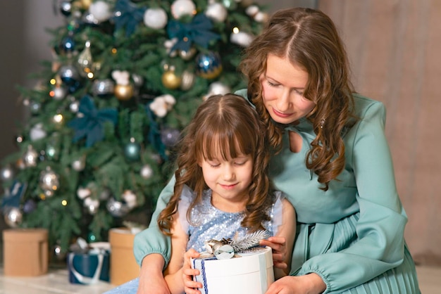 Feliz Navidad y felices fiestas madre alegre y su hija linda niña intercambiando regalos padre a