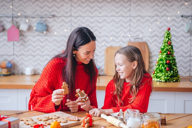 Feliz Navidad y Felices Fiestas. Madre e hija cocinando galletas.