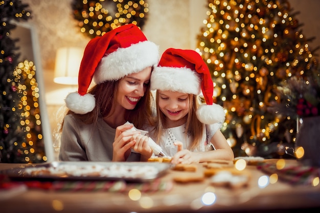 Feliz Navidad y felices fiestas. Madre e hija cocinar galletas de Navidad.