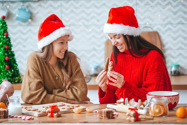 Feliz Navidad y Felices Fiestas. Madre y sus hijas cocinando galletas navideñas