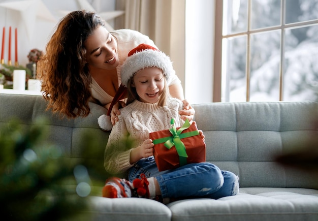 Foto feliz navidad y felices fiestas mamá alegre y su linda hija intercambiando regalos