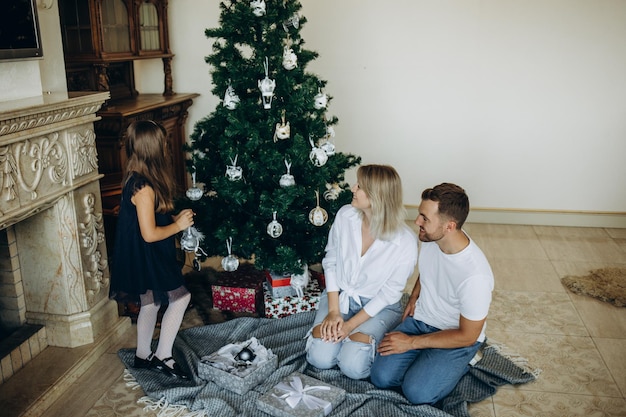 Feliz Navidad y Felices Fiestas Mamá alegre y sus lindas hijas intercambian regalos Padres y dos niños pequeños divirtiéndose y jugando juntos cerca del árbol de Navidad en el interior