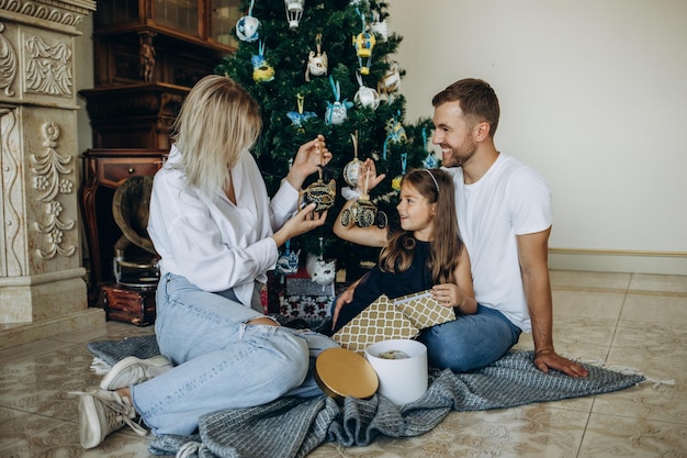 Feliz Navidad y Felices Fiestas Mamá alegre y sus lindas hijas intercambian regalos Padres y dos niños pequeños divirtiéndose y jugando juntos cerca del árbol de Navidad en el interior