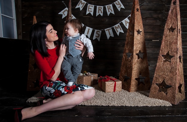 ¡Feliz Navidad y Felices Fiestas! Mamá y su lindo hijo con regalos.