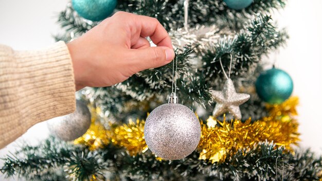 Feliz Navidad y felices fiestas, la mano de un hombre está decorando el abeto en el interior de la casa en invierno. Estrellas de Navidad colgando de ramas de abeto para banner de decoración, concepto de año nuevo.