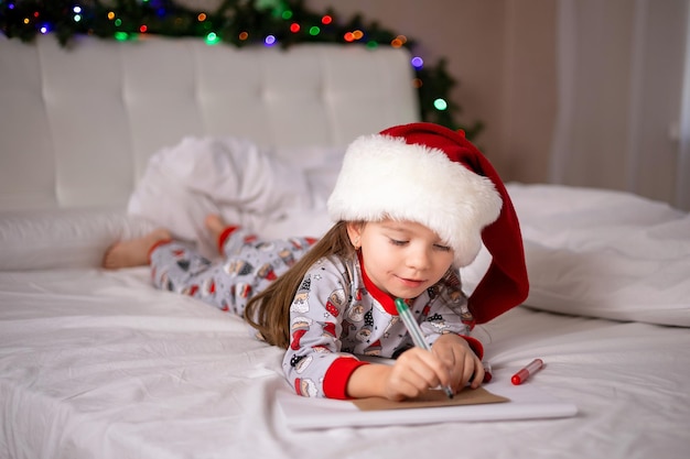 Feliz Navidad y Felices Fiestas La niña feliz en la cama le escribió una carta a Santa Claus