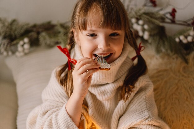 Feliz Navidad y Felices Fiestas. El niño comiendo galletas de jengibre. Esperando la Navidad.