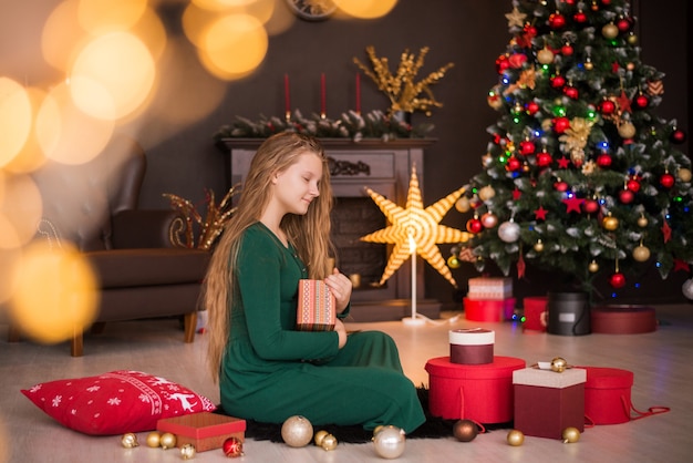 Feliz Navidad y Felices Fiestas. Regalos de apertura linda chica adolescente alegre.