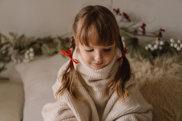 Feliz Navidad y Felices Fiestas. Retrato de una niña en casa. Esperando la Navidad.