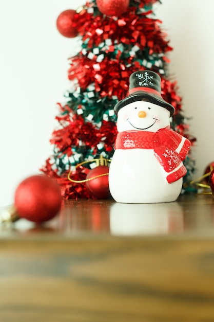 Foto feliz navidad y feliz año nuevo decoración con muñeco de nieve en el piso de madera.