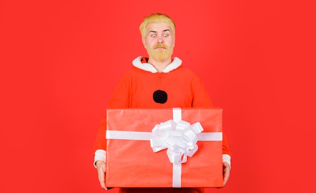 Foto feliz navidad y feliz año nuevo servicio de entrega hombre barbudo en traje de papá noel con regalo de navidad