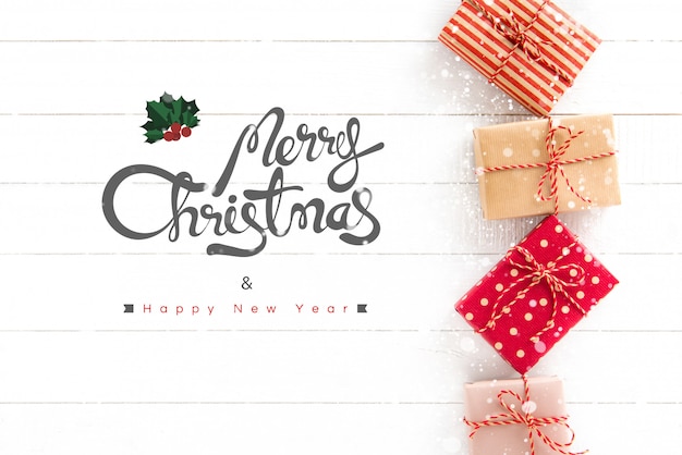 Feliz Navidad y feliz año nuevo texto con cajas de regalo sobre fondo blanco de madera