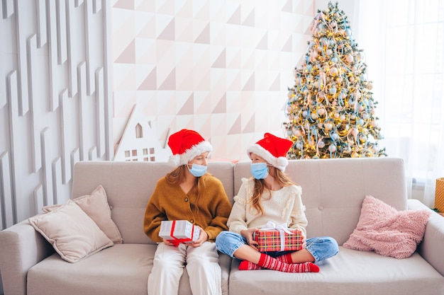 Feliz Navidad. Hermosas chicas con regalos en Navidad. Los niños usan mascarillas