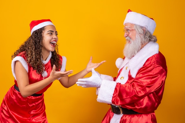 Feliz Navidad. Joven noelete y verdadero Santa Claus interactuando jugando sobre fondo amarillo