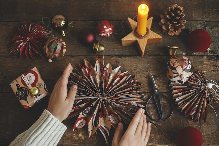 Foto feliz navidad manos sosteniendo la estrella de navidad hecha de papel de regalo sobre una mesa rústica plana