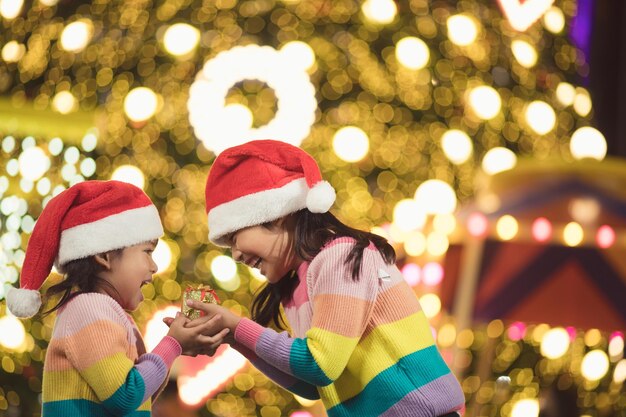 Feliz Navidad a los niños felices con un regalo mágico en casa cerca del árbol de Navidad