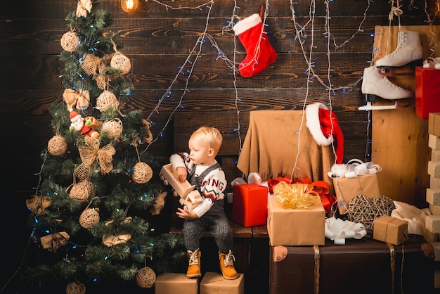 Feliz navidad y próspero año nuevo bebés retrato niño con regalo sobre fondo de madera niño feliz con ...