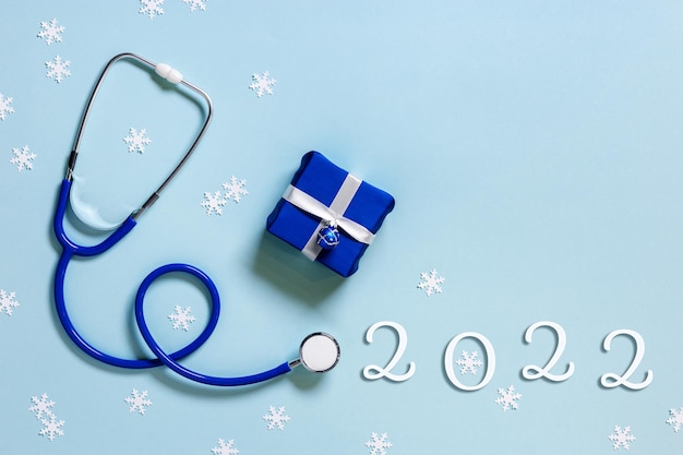 Feliz Navidad y próspero año nuevo concepto de medicina estetoscopio azul copos de nieve pequeña caja de regalo