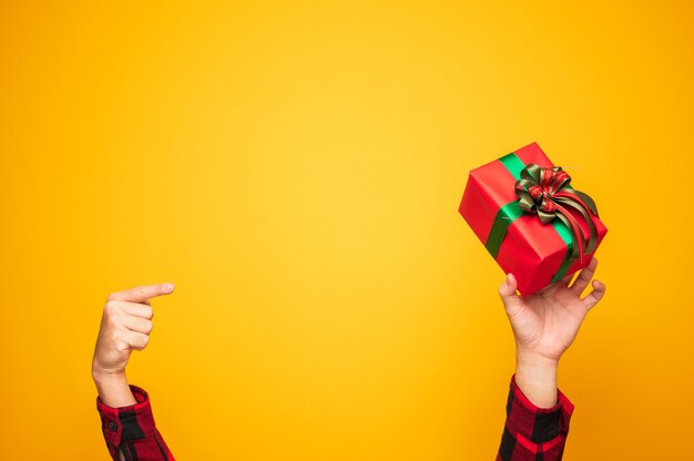 Foto feliz navidad y próspero año nuevo manos masculinas apuntando la caja de regalo actual