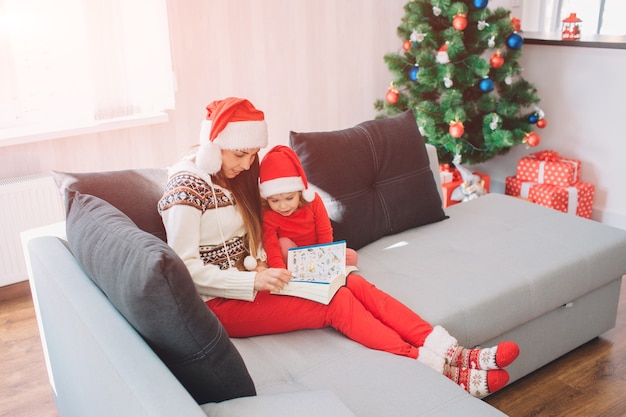 Feliz navidad y próspero año nuevo. Mujer joven, sentarse, en, sofá, con, hija