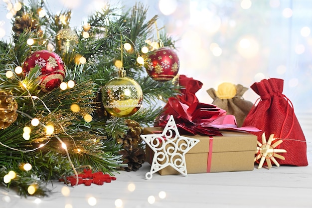 Feliz Navidad. Regalos de Navidad y sorpresas en una mesa de madera blanca junto a las ramas de un árbol de Navidad y luces brillantes. Tarjeta de felicitación o banner para sitio web.