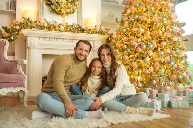 Feliz Navidad. Sonriente familia feliz sentada en el suelo cerca del árbol de Navidad