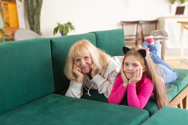 Feliz nieta y abuela acostada en el sofá en pose divertida abuela divirtiéndose con nieto