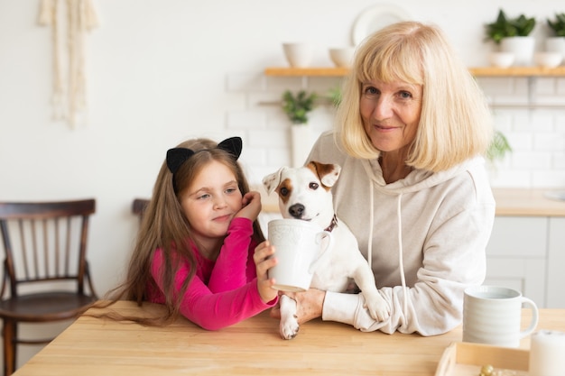 Feliz nieta y abuela en la cocina con la abuela de perro jack russell terrier y