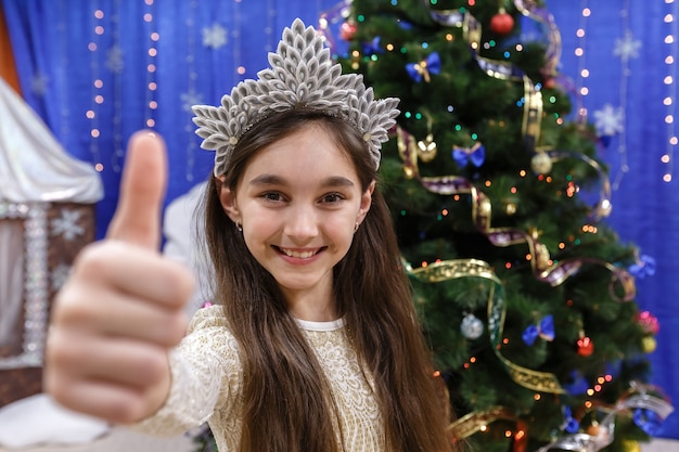 Feliz niña de 10 años muestra el pulgar hacia arriba, firme bien