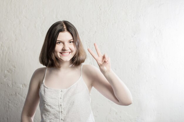 Feliz niña adolescente morena en la pared de fondo blanco