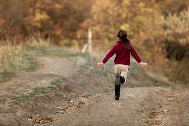 Feliz niña adorable corre en el parque de otoño